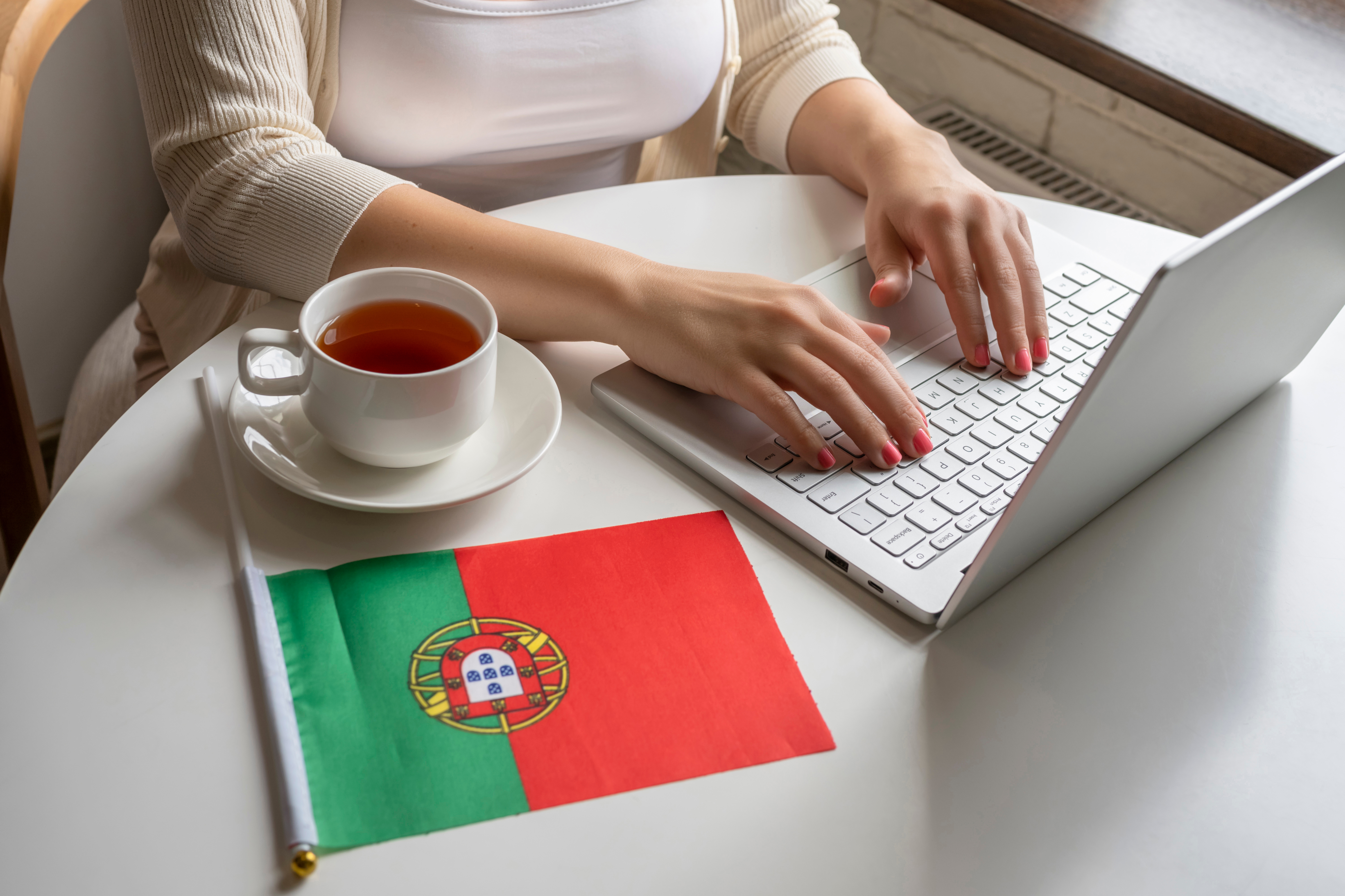 Девушка сидит за компьютером возле флага Португалии, где работа доступна для иностранцев