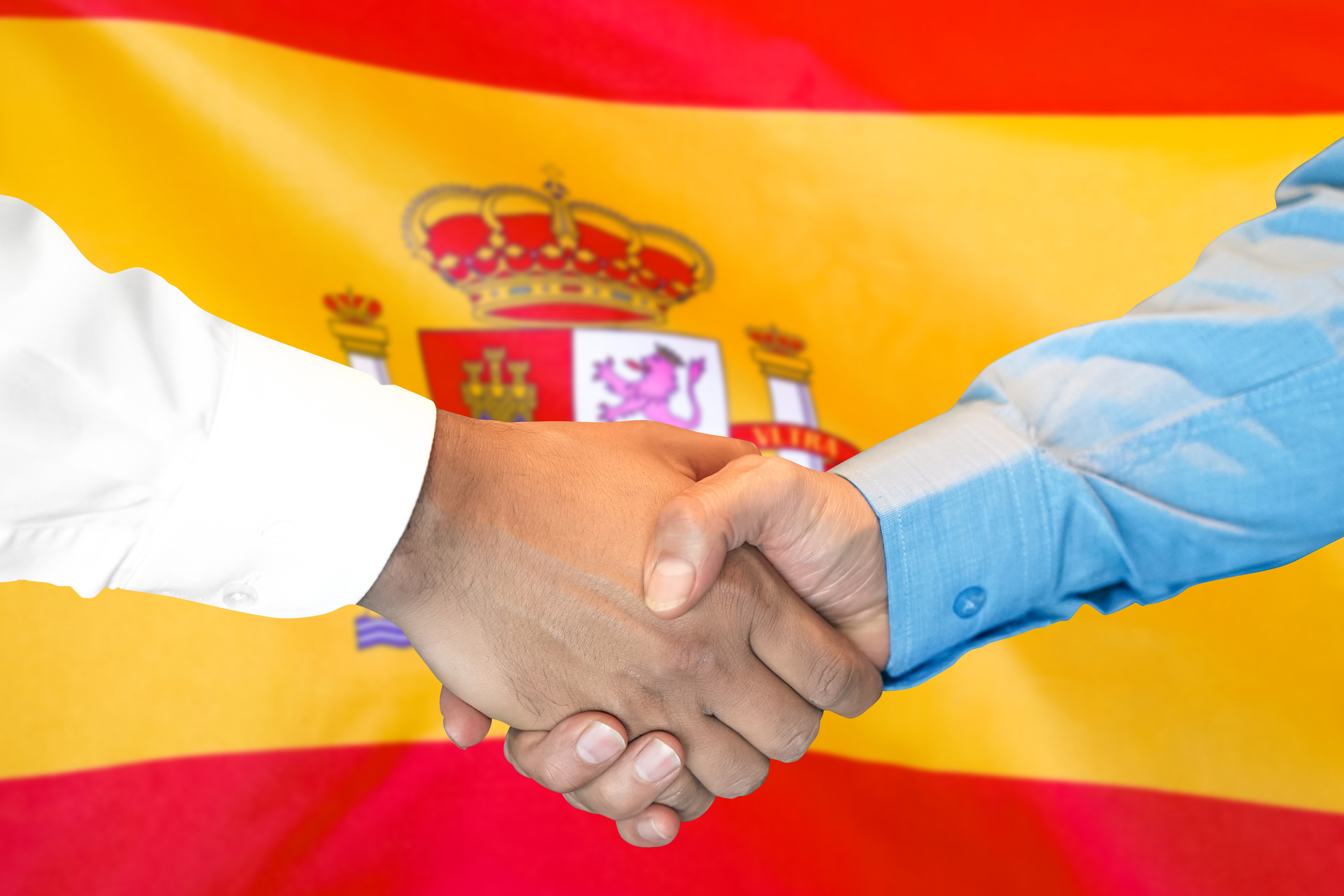 Рукопожатие на фоне флага Испании, работа в которой доступна для иностранцев